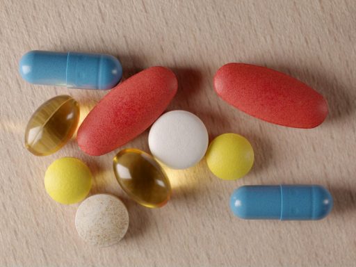 Close-up of various pills and capsules in different colors on a wooden surface.