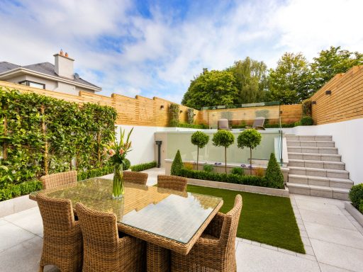 a patio with a table and chairs next to a fence