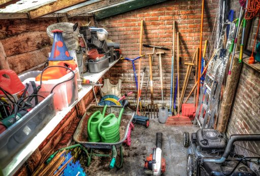 Tuingereedschap inclusief grastrimmer opgehangen in een tuinschuur