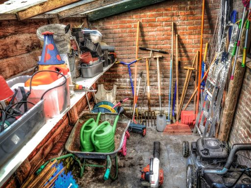 Tuingereedschap inclusief grastrimmer opgehangen in een tuinschuur