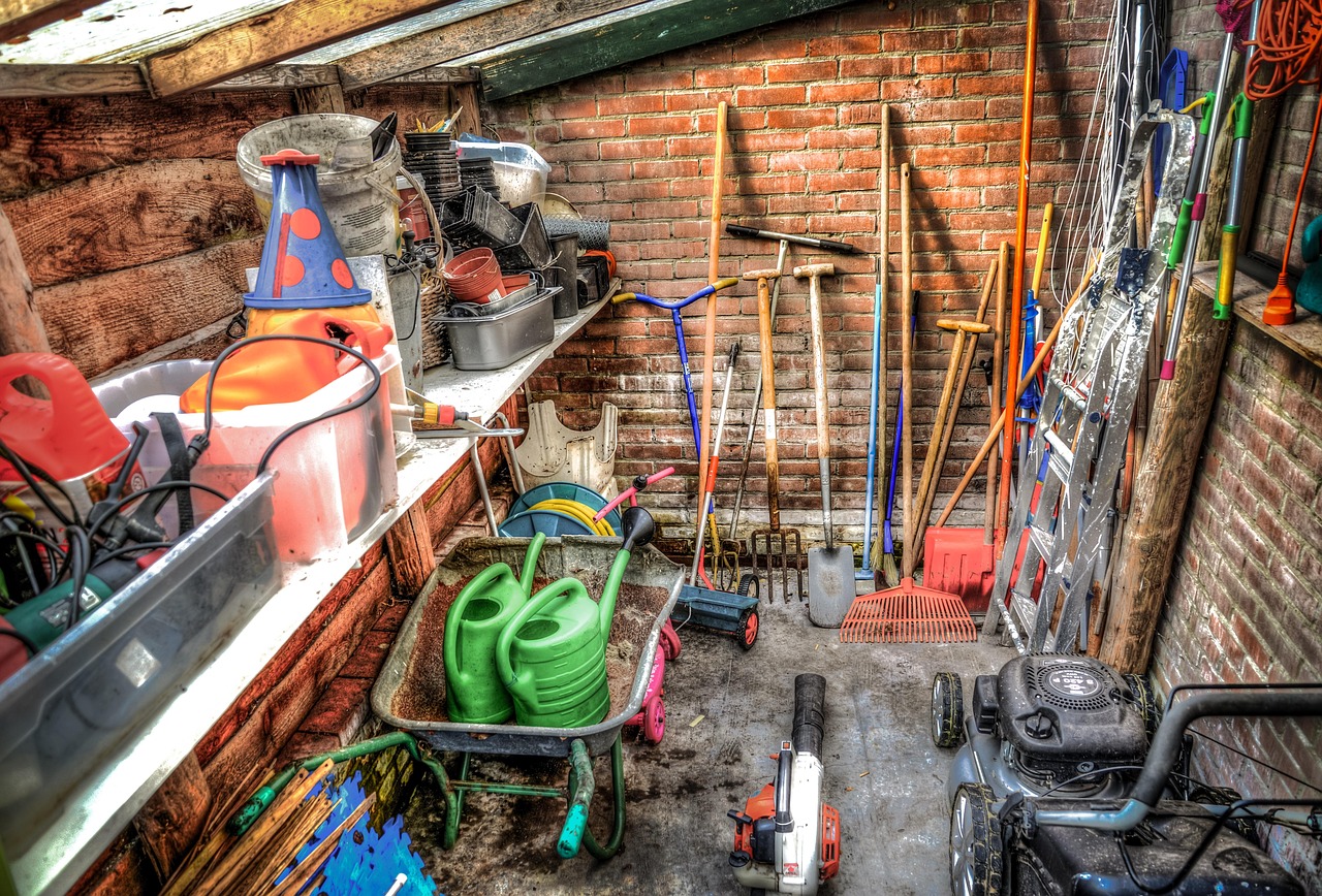 Tuingereedschap inclusief grastrimmer opgehangen in een tuinschuur