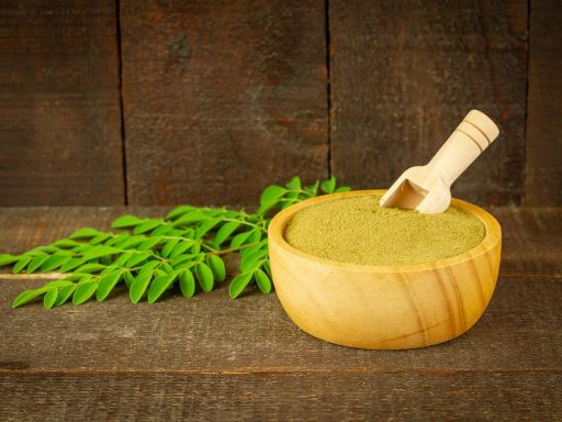Een schep creatinepoeder naast een pot supplement op een sportieve achtergrond