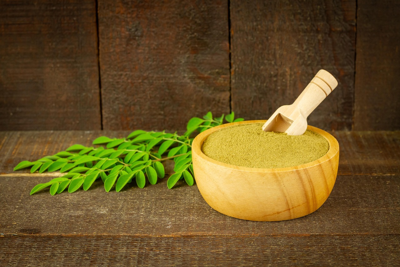 Een schep creatinepoeder naast een pot supplement op een sportieve achtergrond