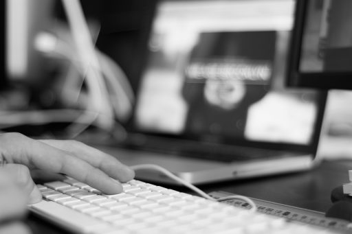 Persoon die achter een laptop een domeinnaam registreert en registrars vergelijkt