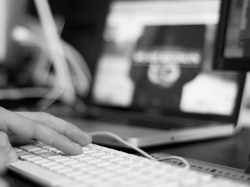 Persoon die achter een laptop een domeinnaam registreert en registrars vergelijkt